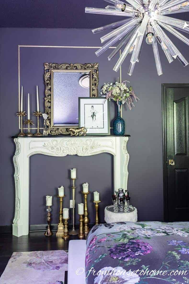 A dark purple bedroom with a white fireplace mantel