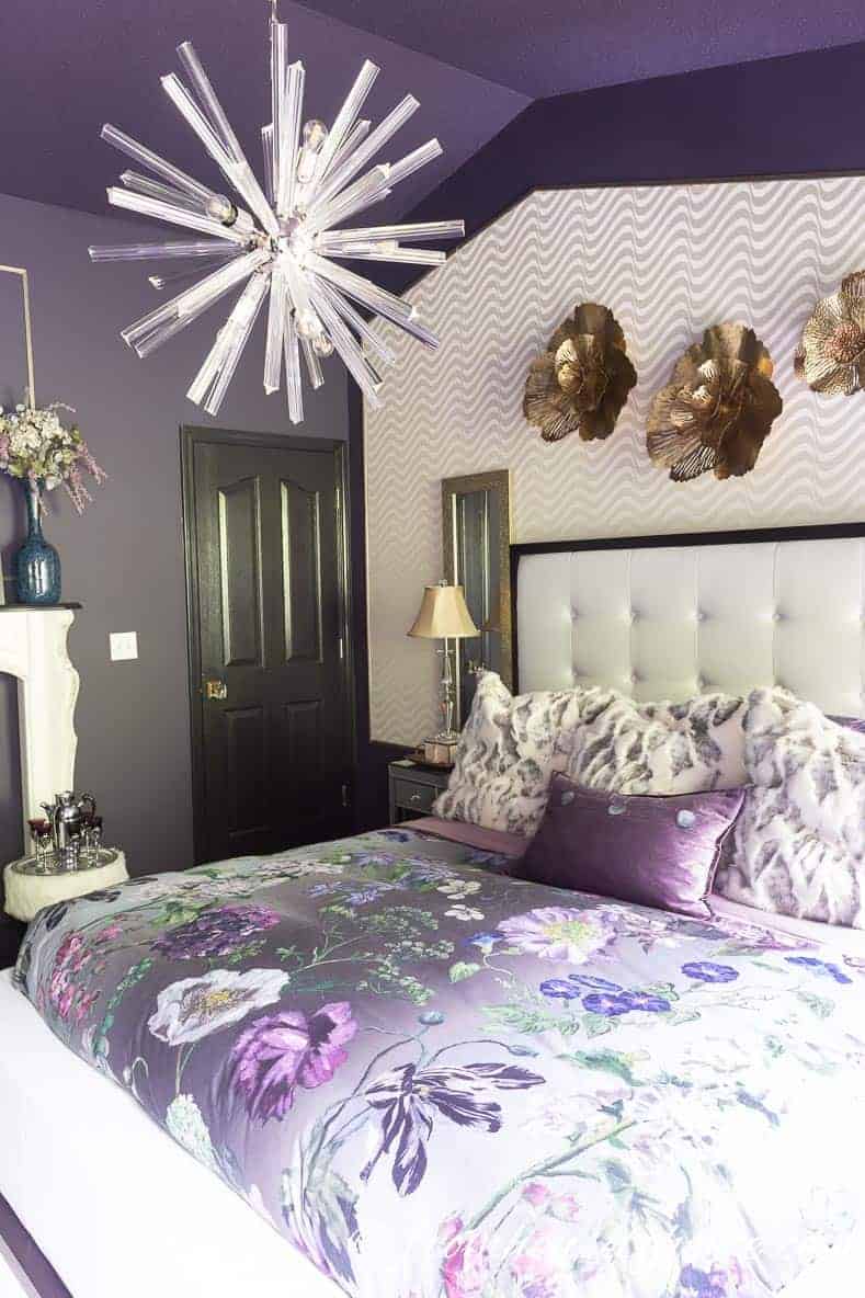 The white wallpaper behind the bed helps to brighten up the purple walls