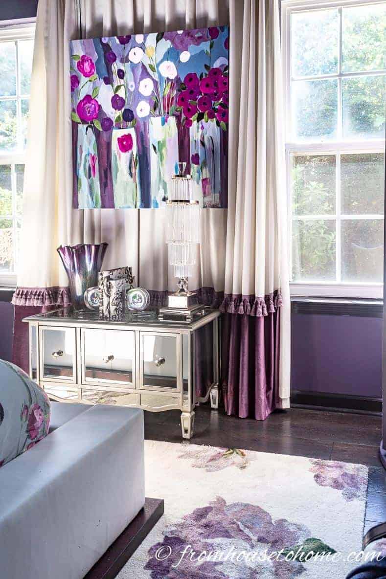 A purple bedroom with white and purple curtains and area rug
