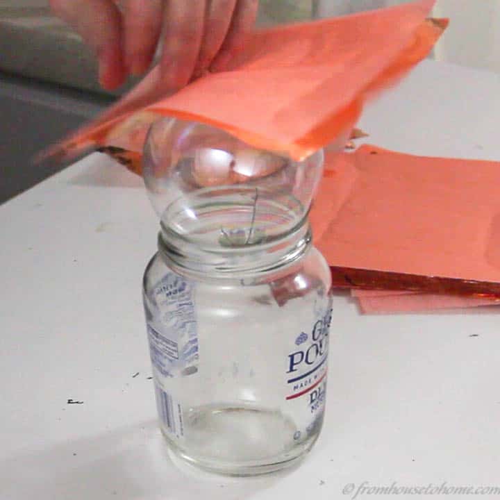 Copper leaf being applied to a glass Christmas ornament, using a jar as a stand