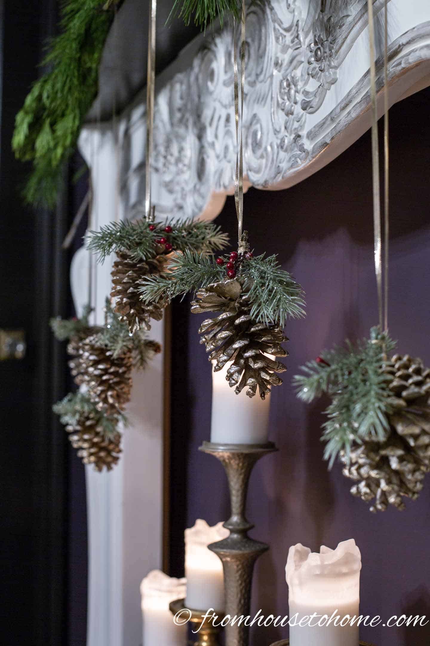 DIY pine cone ornaments hung from the fireplace mantel