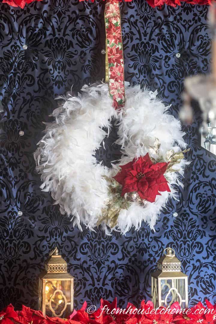 DIY white feather Christmas wreath hung with red poinsettia ribbon