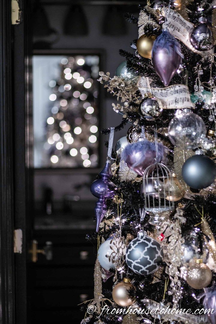 Purple and gold ornaments with white ribbon on a Christmas tree
