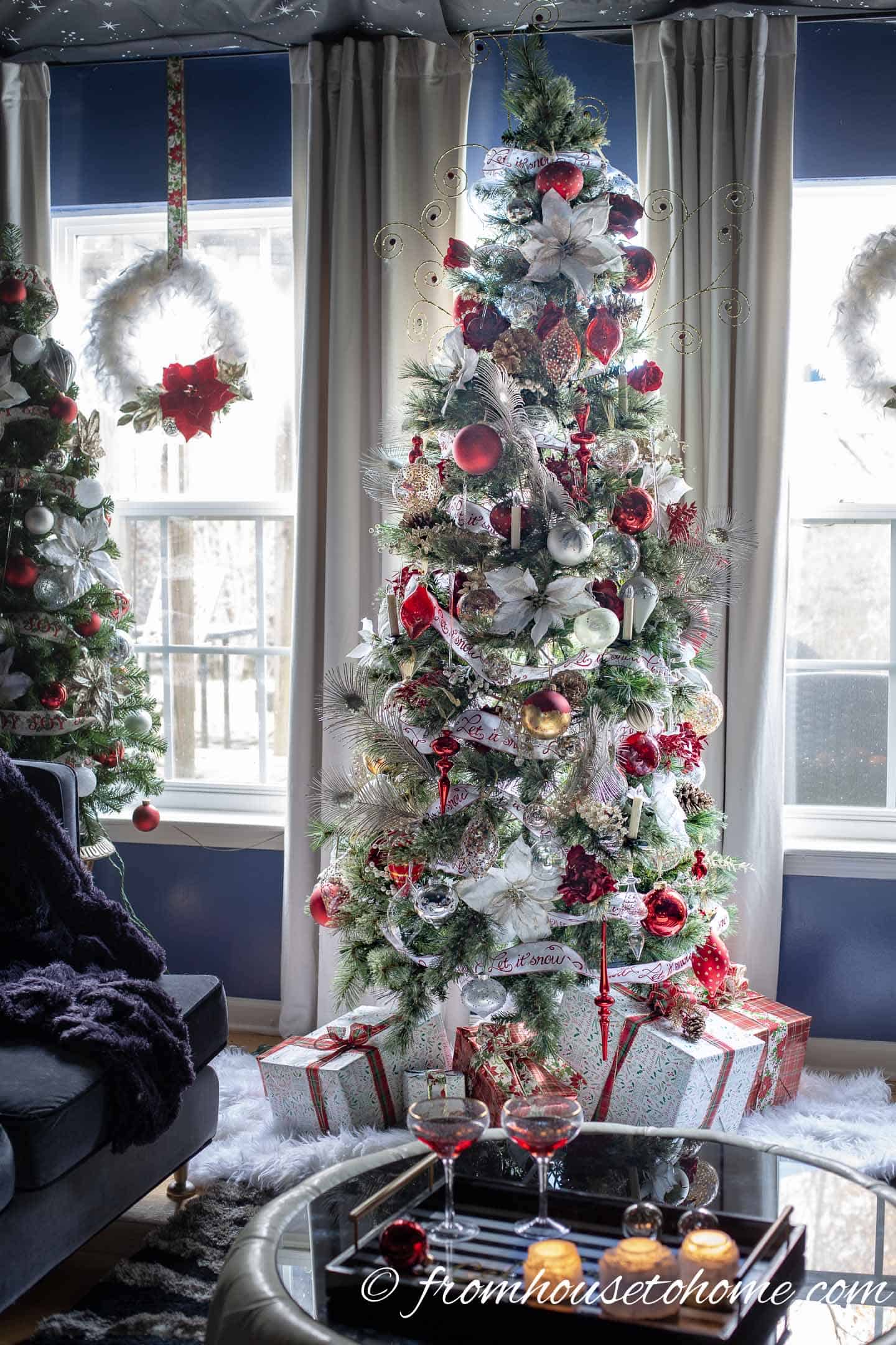 Christmas tree in front of windows with white, red and gold wreaths hanging in them