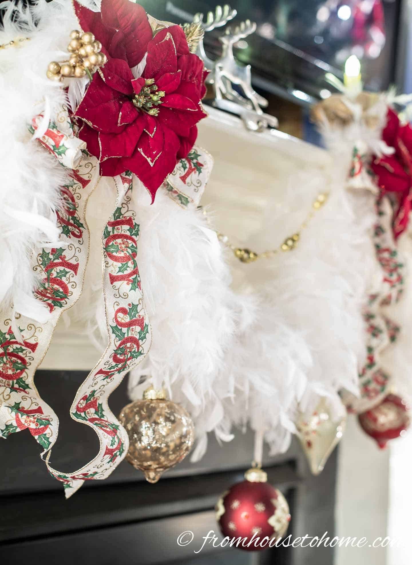 White feather boa, ribbons and red poinsettia clips decorating a fireplace mantel for Christmas