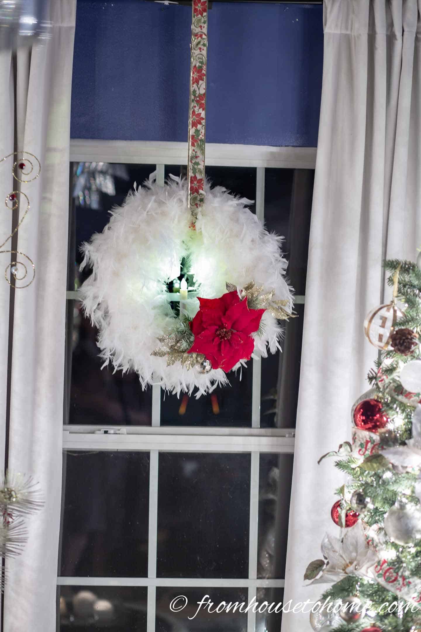 White, red and gold wreath hanging in front of a window