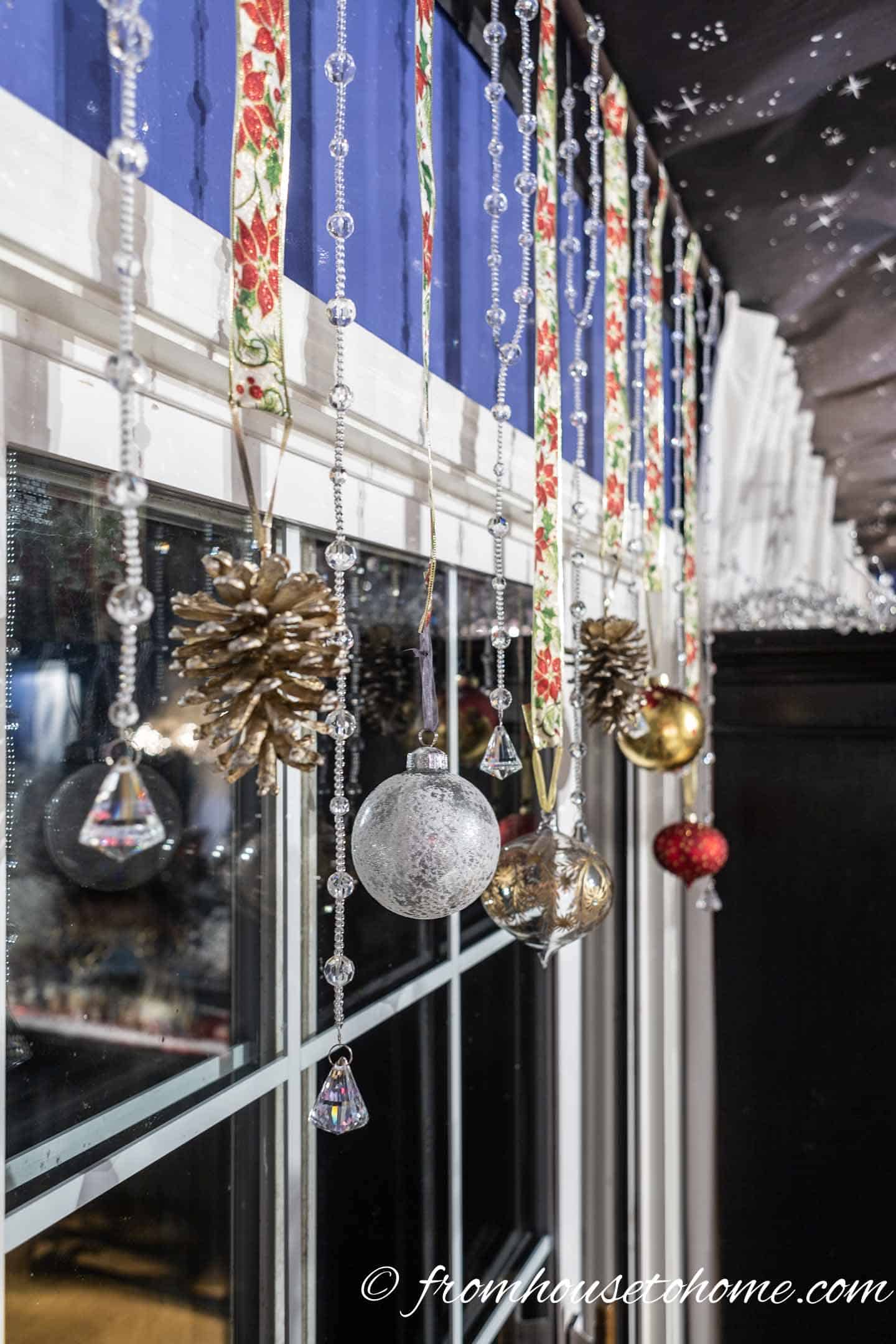 Close up of red, white and gold Christmas ornaments hung in front of a window