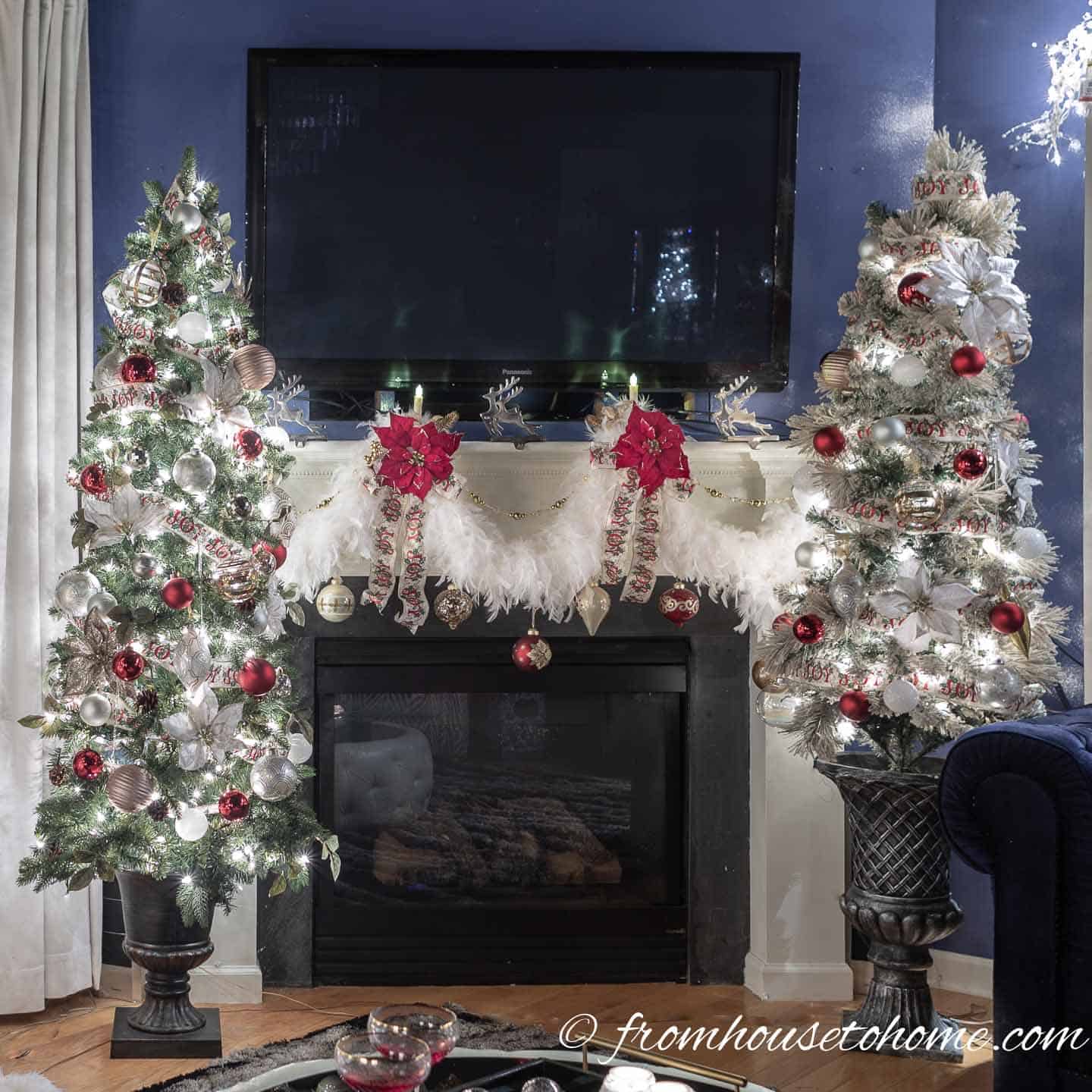 Two red, white and gold Christmas trees on either side of the fireplace