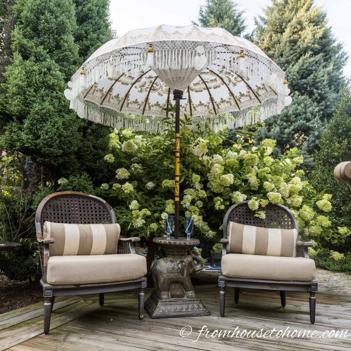 White and gold Balinese umbrella with white fringe over two deck chairs