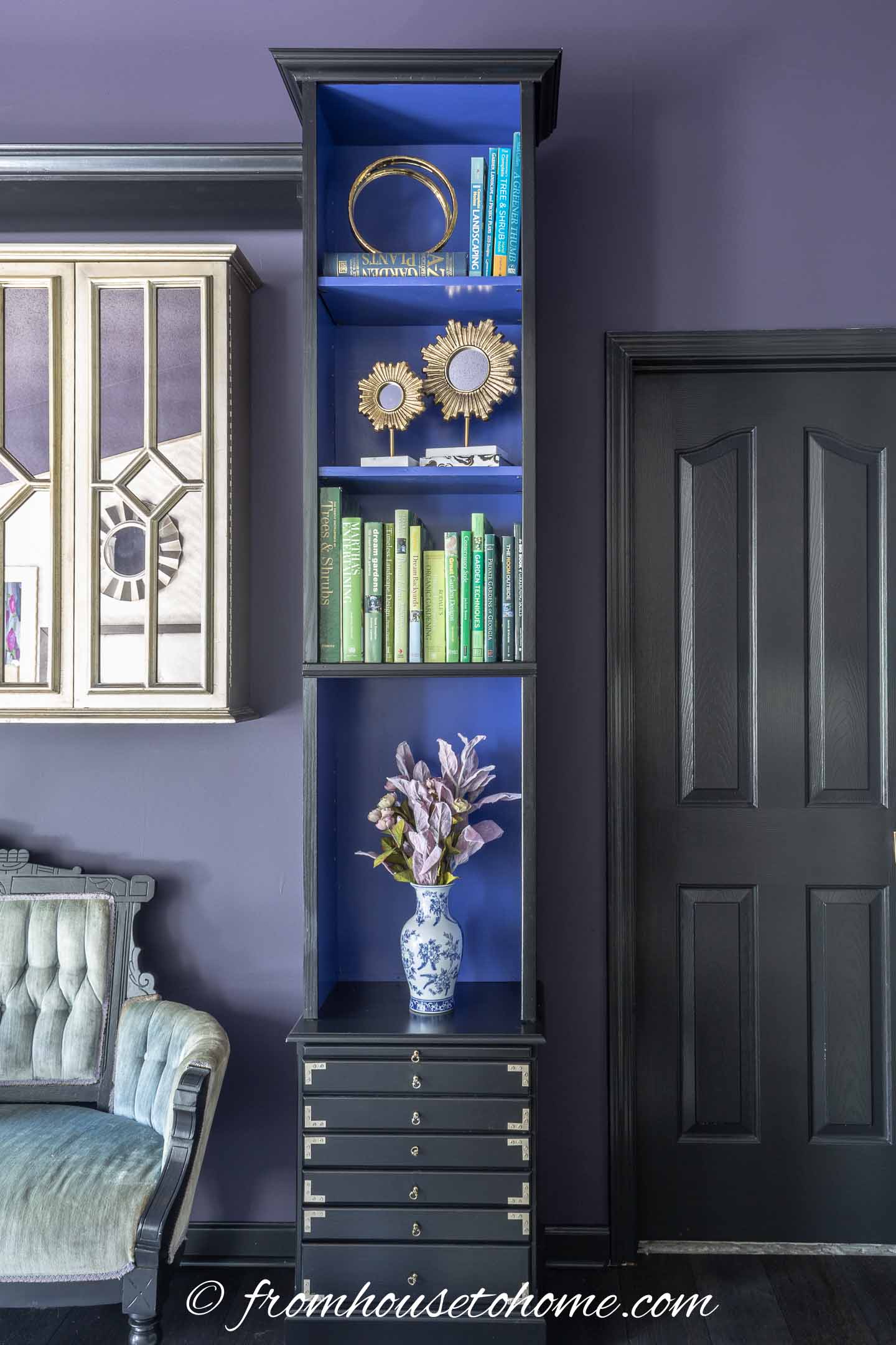 A black and blue bookshelf in a bedroom with dark purple walls