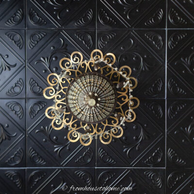 gold chandelier on a black faux tin ceiling