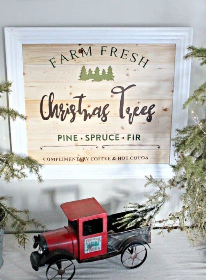 Christmas tree farm sign on a mantel with a red truck