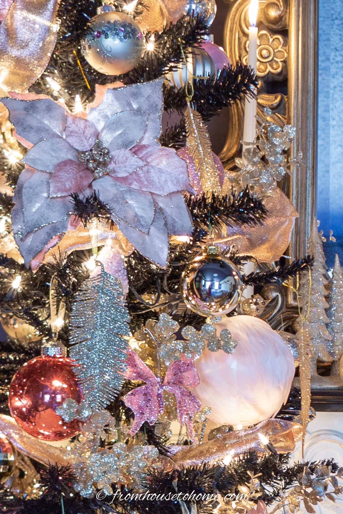 Black Christmas tree with pink poinsettia pick and feather-covered pink ornament