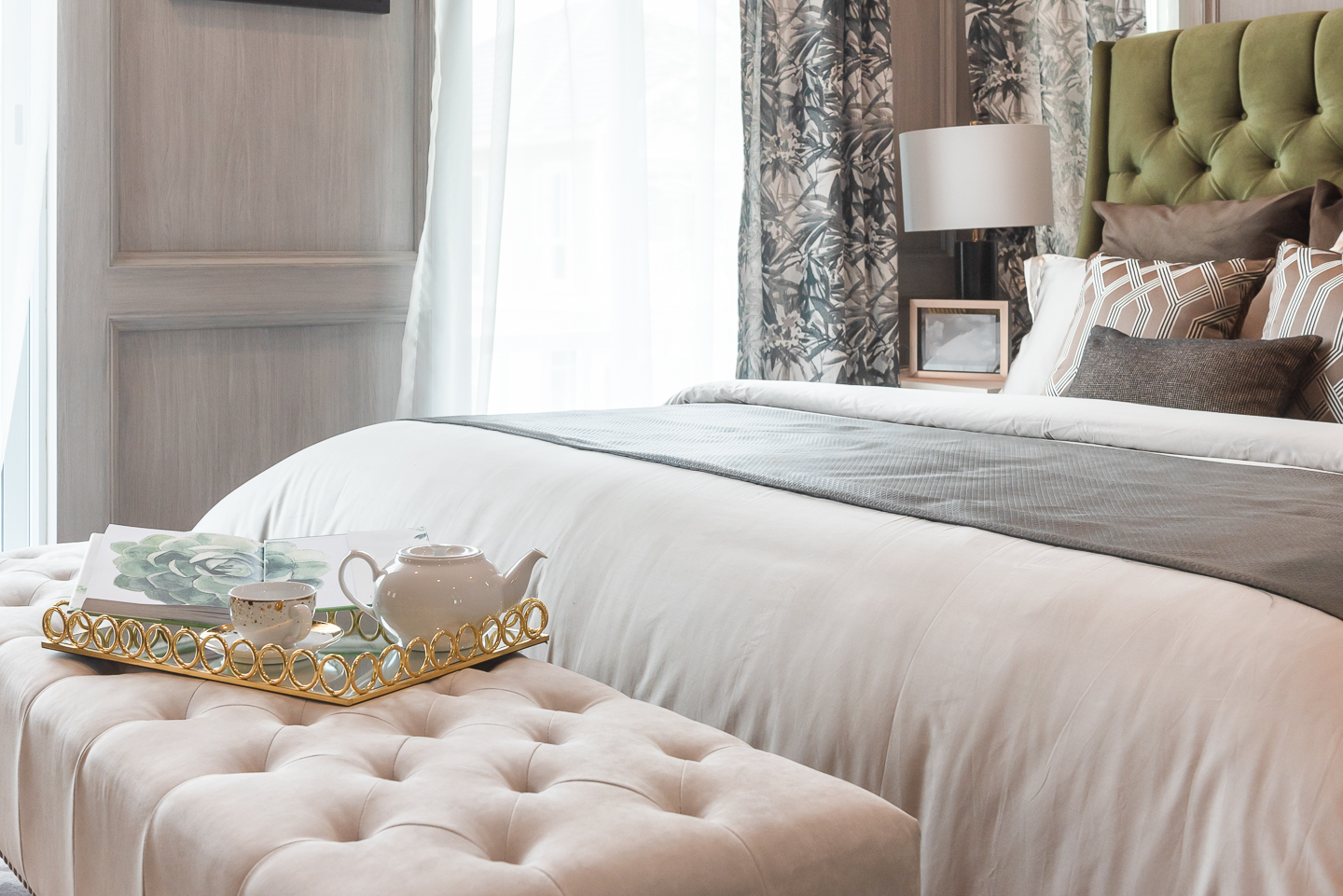 Bed with layers of bedding and a bench in a guest bedroom