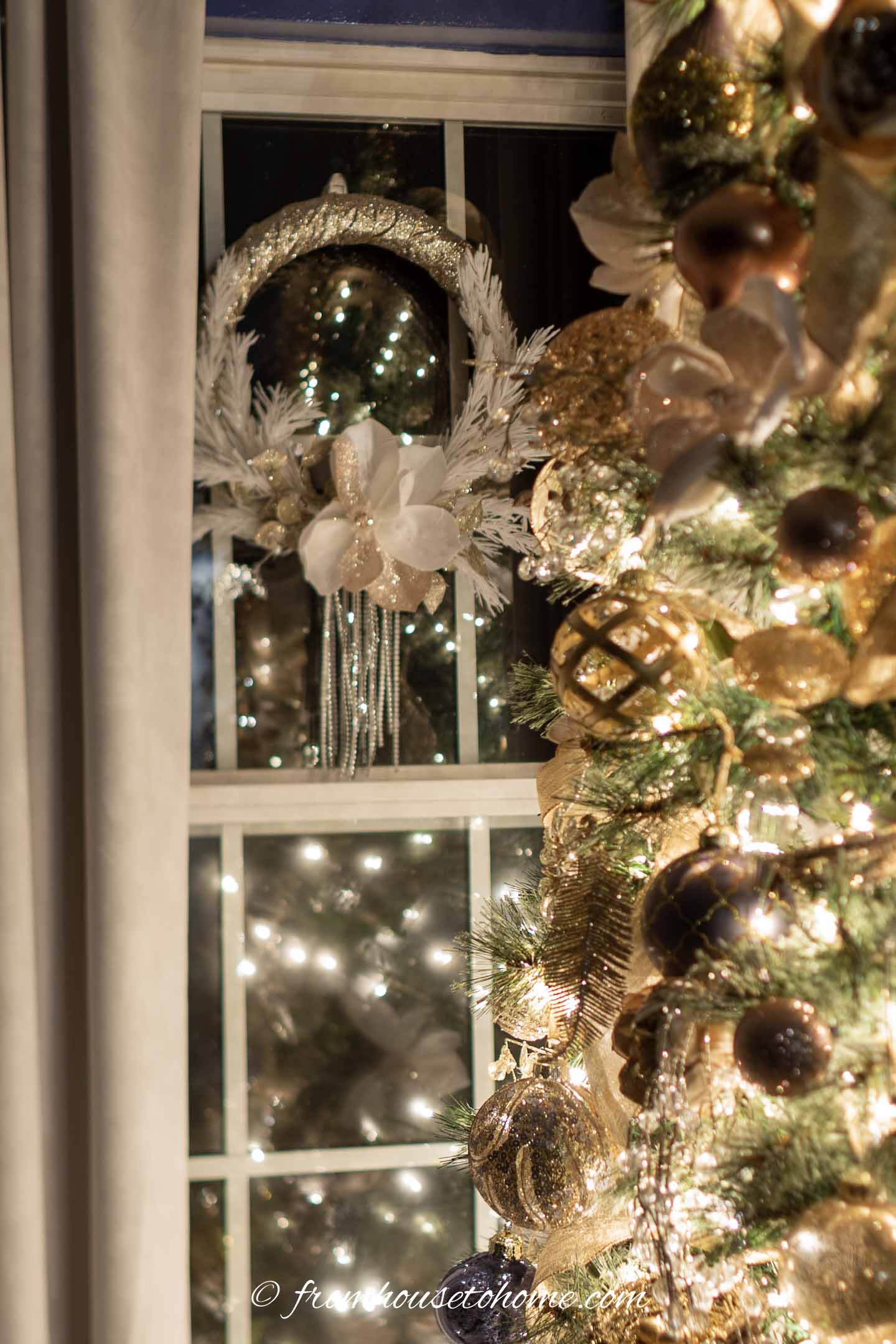 Gold and white wreath hung in the window behind the Christmas tree