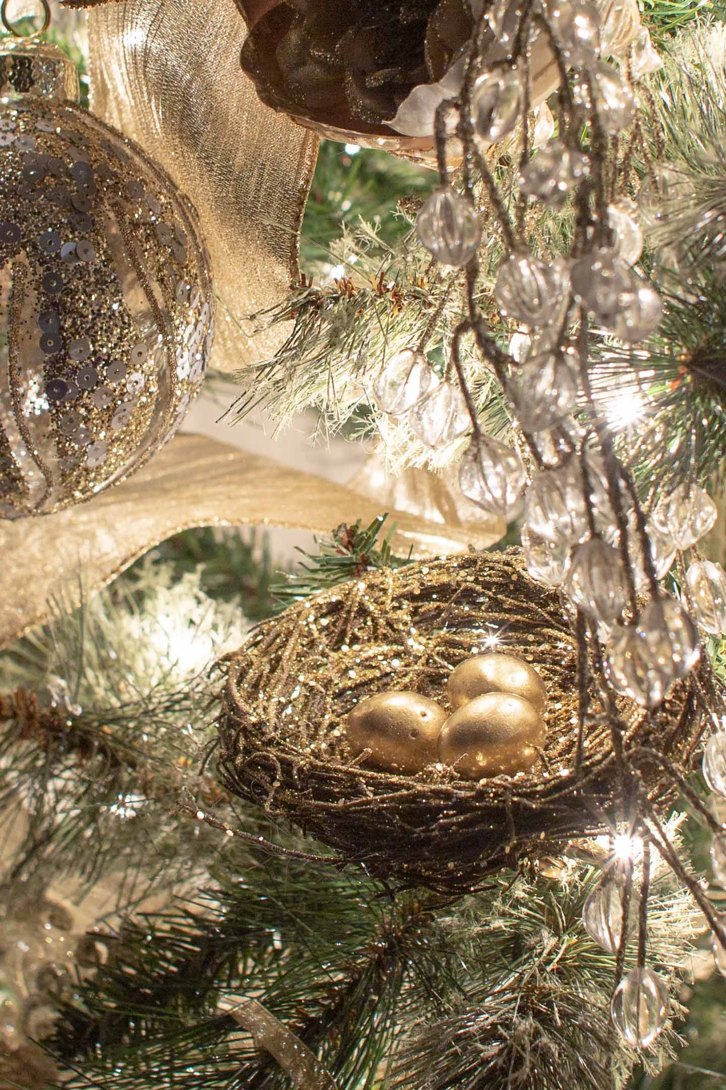 Gold DIY bird's nest ornament on a Christmas tree at night