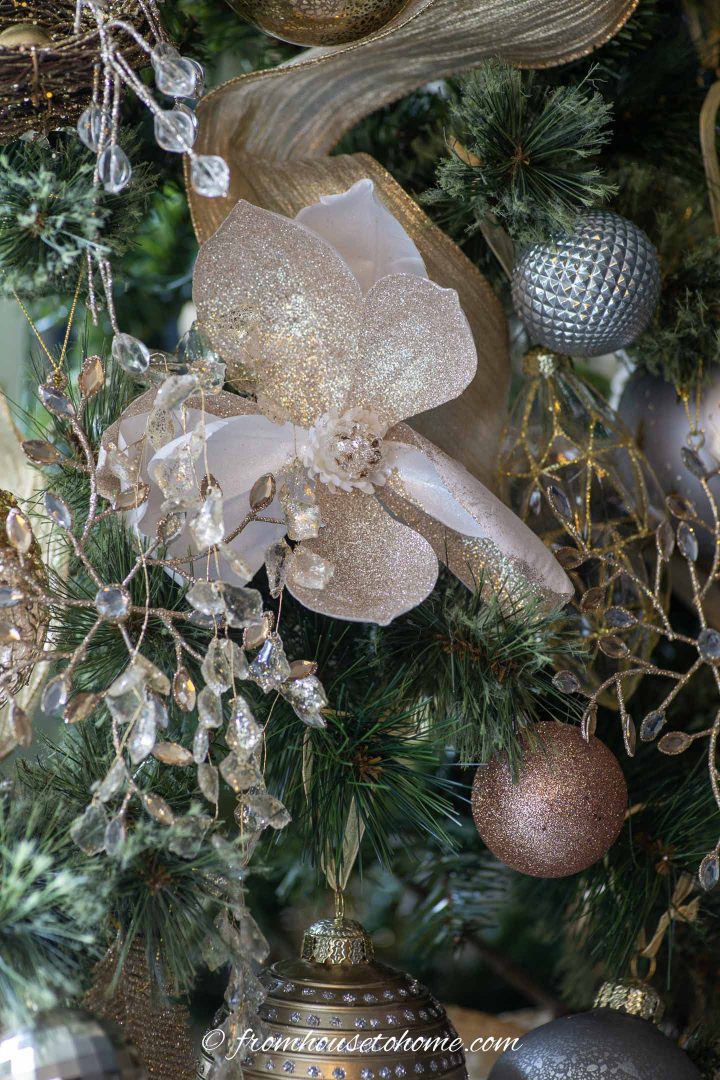 Flor de magnólia branca e dourada com fita dourada em uma árvore de Natal