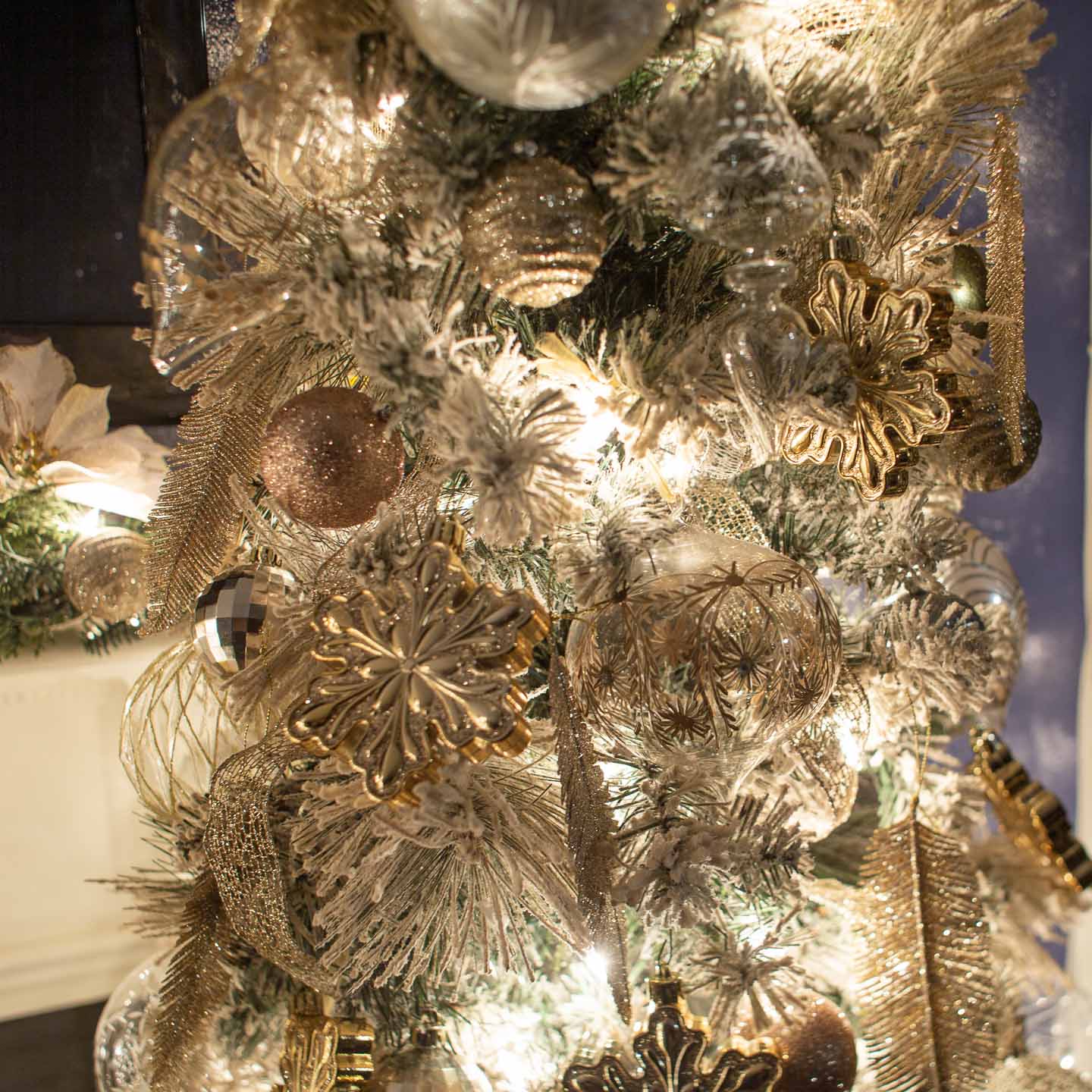 Copper, silver and gold ornaments on a flocked Christmas tree
