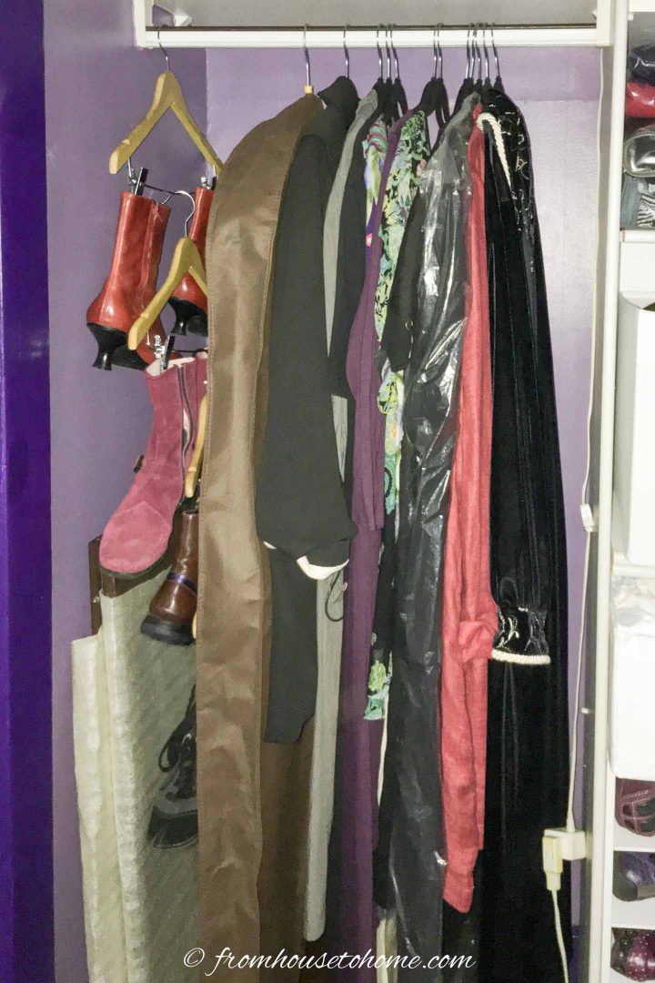 Boots hung on a closet rod beside other jackets and other clothing
