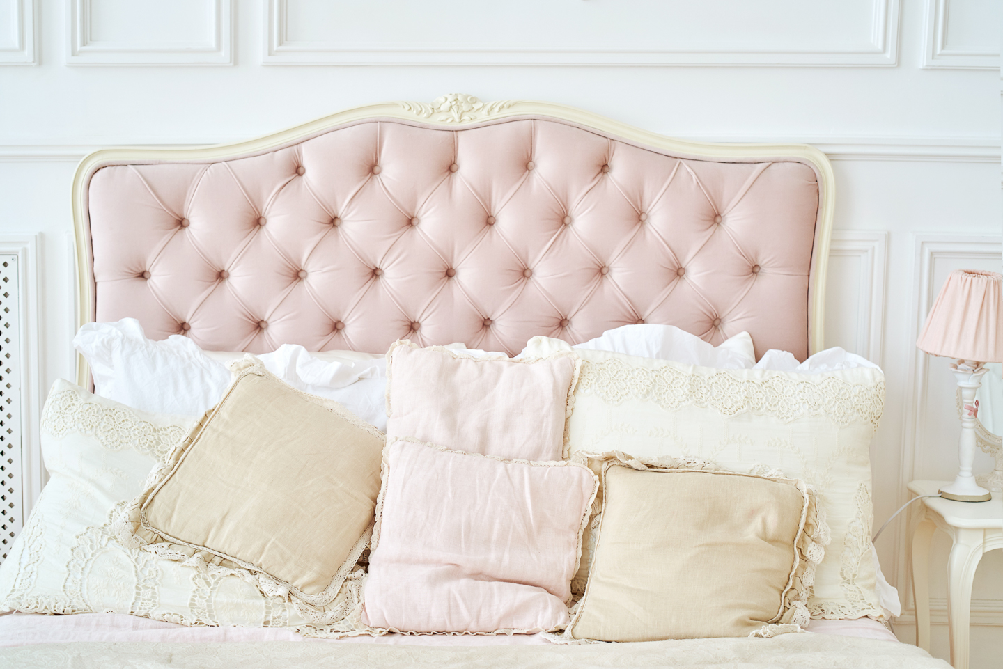 Pink and white headboard behind cushions on the bed