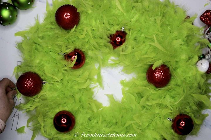 Large and small red Christmas ornaments on a DIY Grinch wreath