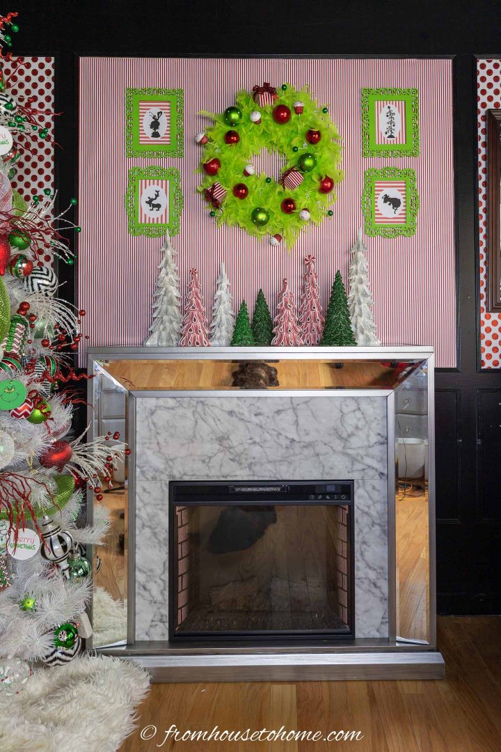 The DIY Grinch wreath hung on the wall above a fireplace.