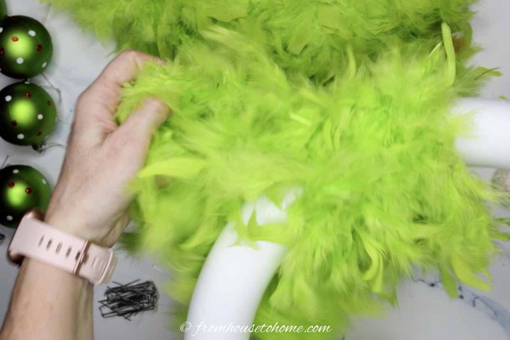 Green feather boa being wrapped around the styrofoam wreath form