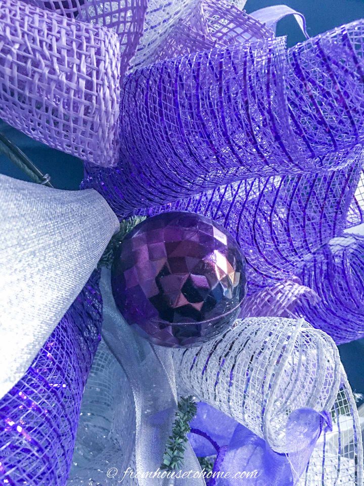 The purple Christmas ornament attached to the deco mesh Christmas wreath