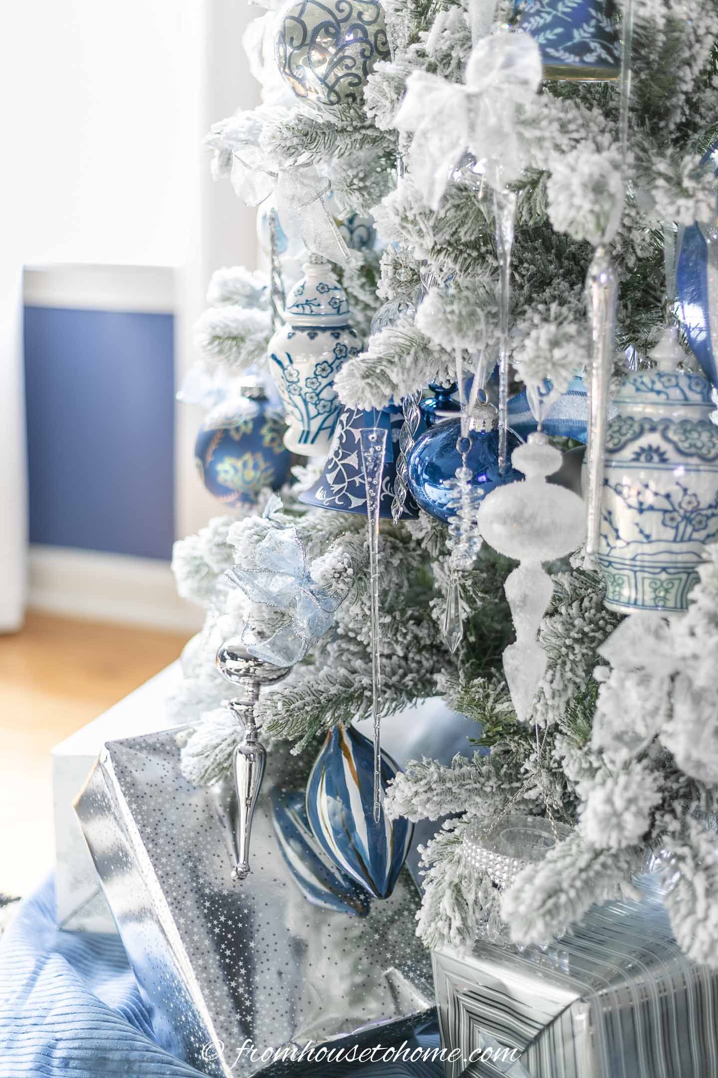 Christmas presents wrapped in silver wrapping paper under a wintry white, blue and silver christmas tree