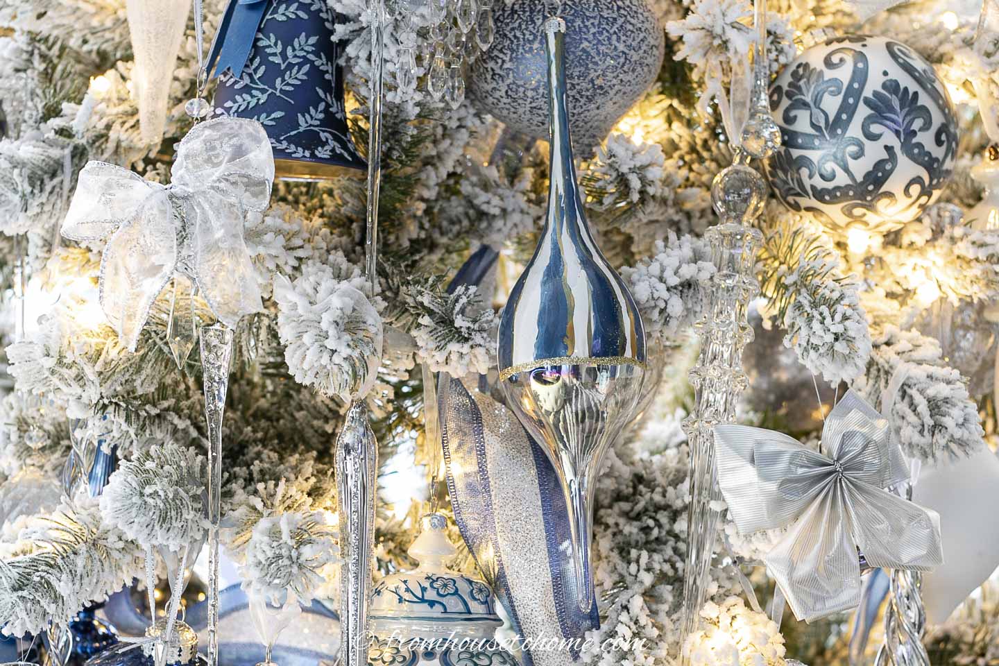 white lace and silver bows tied to the branches of a flocked christmas tree