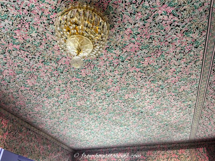 Ceiling covered in floral fabric with a gold and crystal light fixture