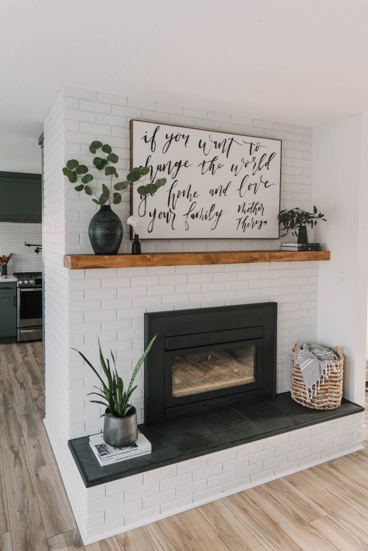 Oversized art print and two faux plants on a fireplace mantel 