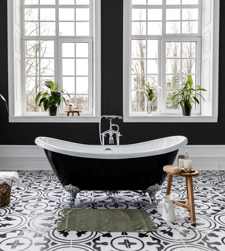 black and white clawfoot tub on a floral pattern black and white tile floor