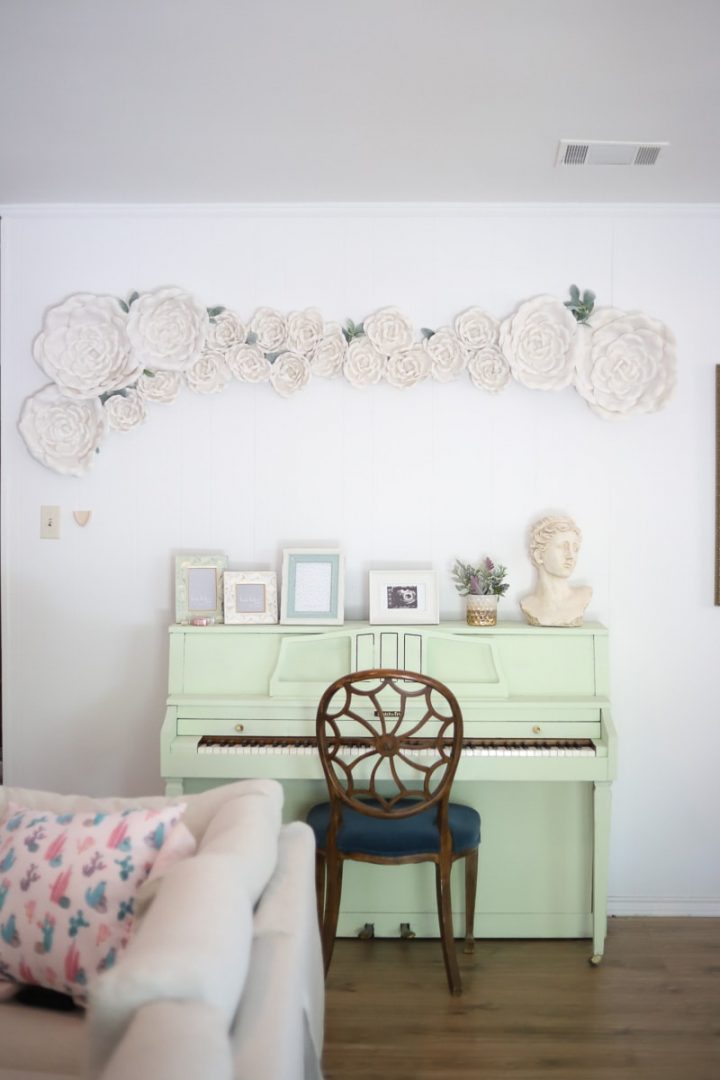 White paper flowers on the wall above the piano