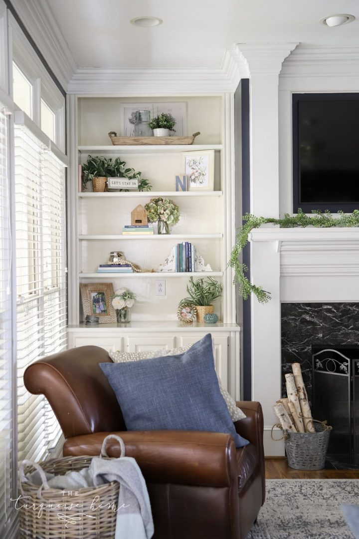 Faux flowers and greenery on an off-white book case. 