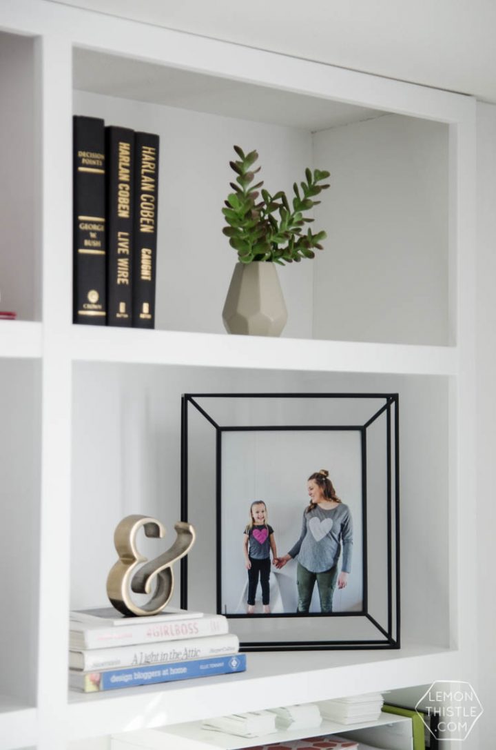 Framed photos on the center shelf of a bookcase. 