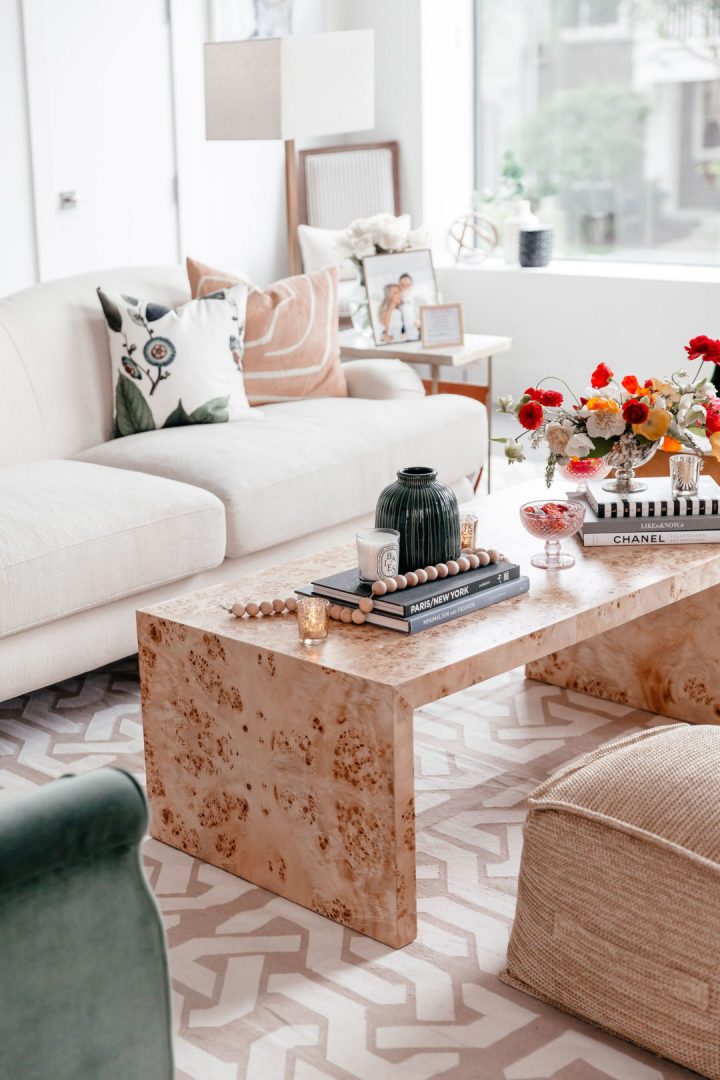 A rectangular coffee table styled with books, vases, flowers, candles, beads and a candy dish.