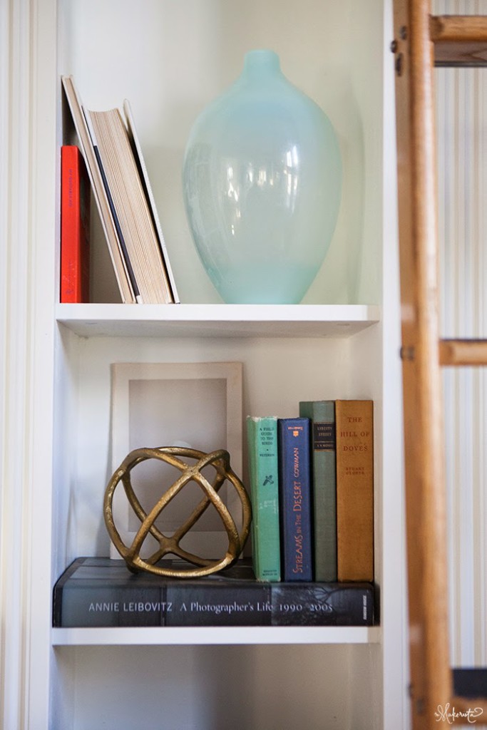Bookshelf featuring a glass vase and a metal geometric decor piece with books