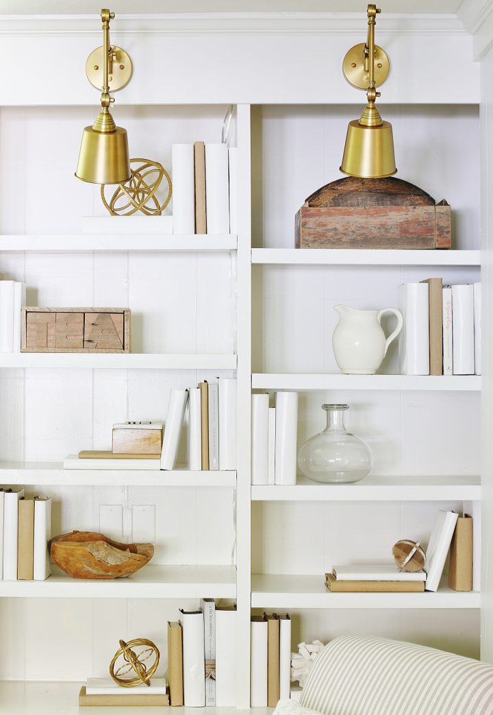 Bookcases decorated with books covered in white and brown covers and vases