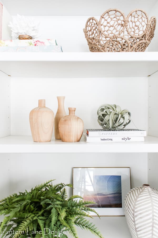 A woven basket as bookshelf decor, accompanied by plants and vases.