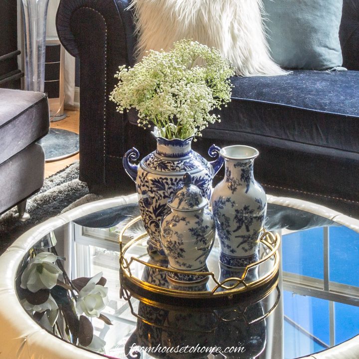 A light reflecting glass topped coffee table with a tray filled with vases on top. 