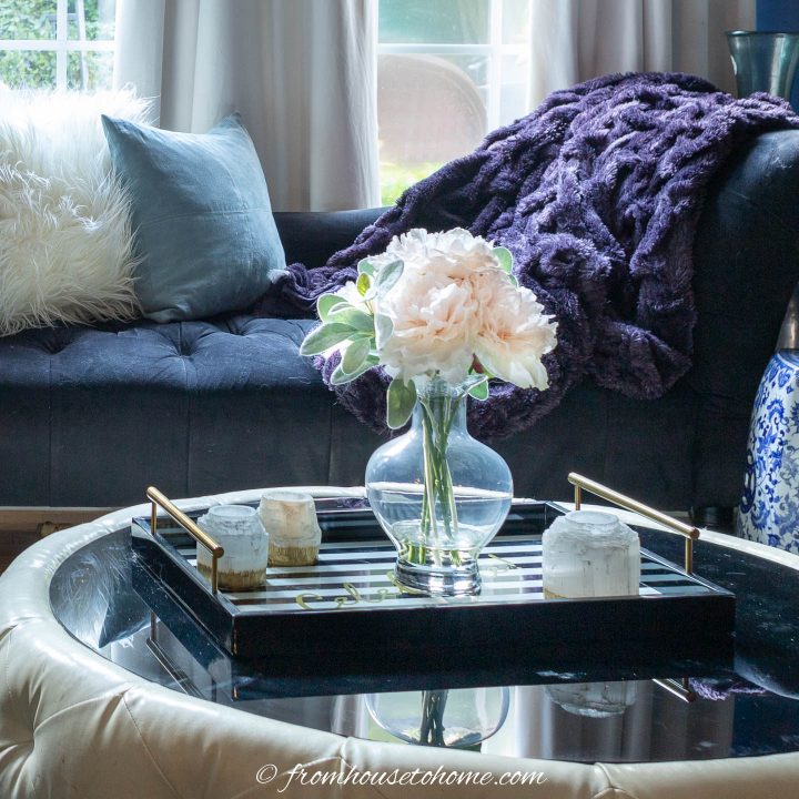 Round coffee table with some candles and faux flowers on a tray
