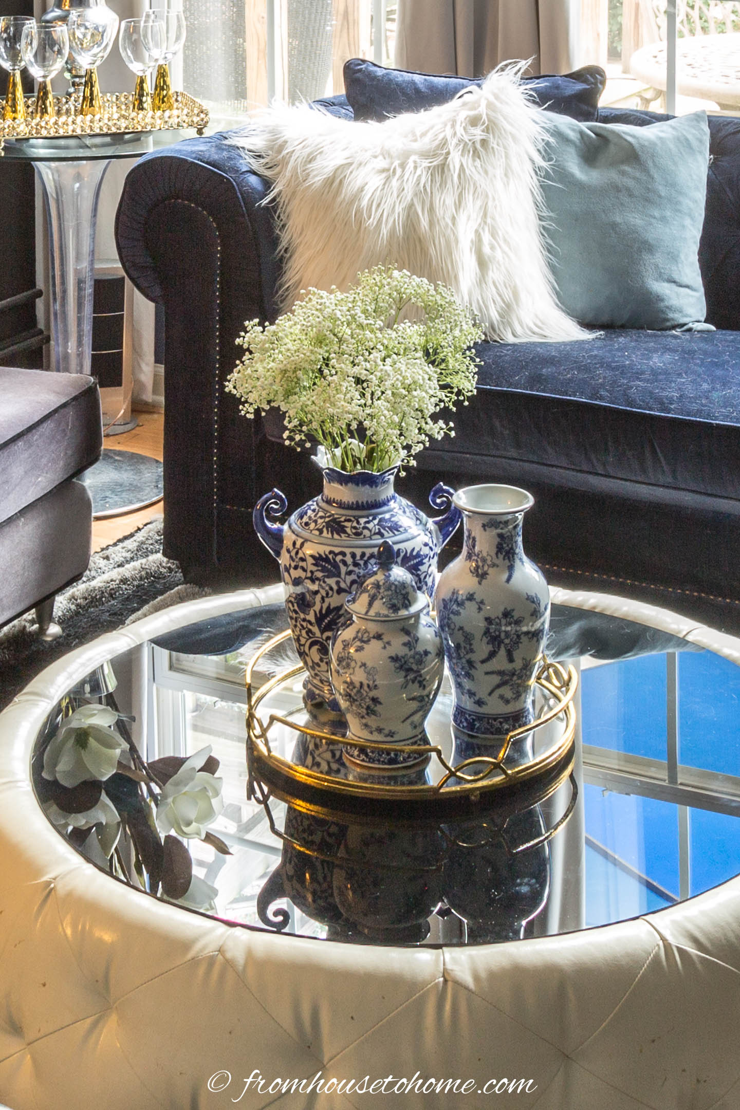 A round living room coffee table with three ginger jars on a round gold tray