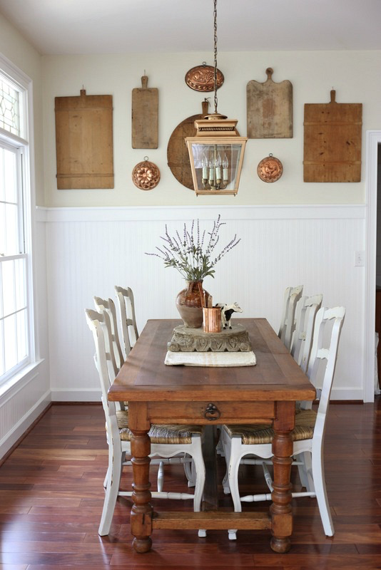 Vintage wooden cutting boards hung on a dining room wall as a gallery-style art display. 
