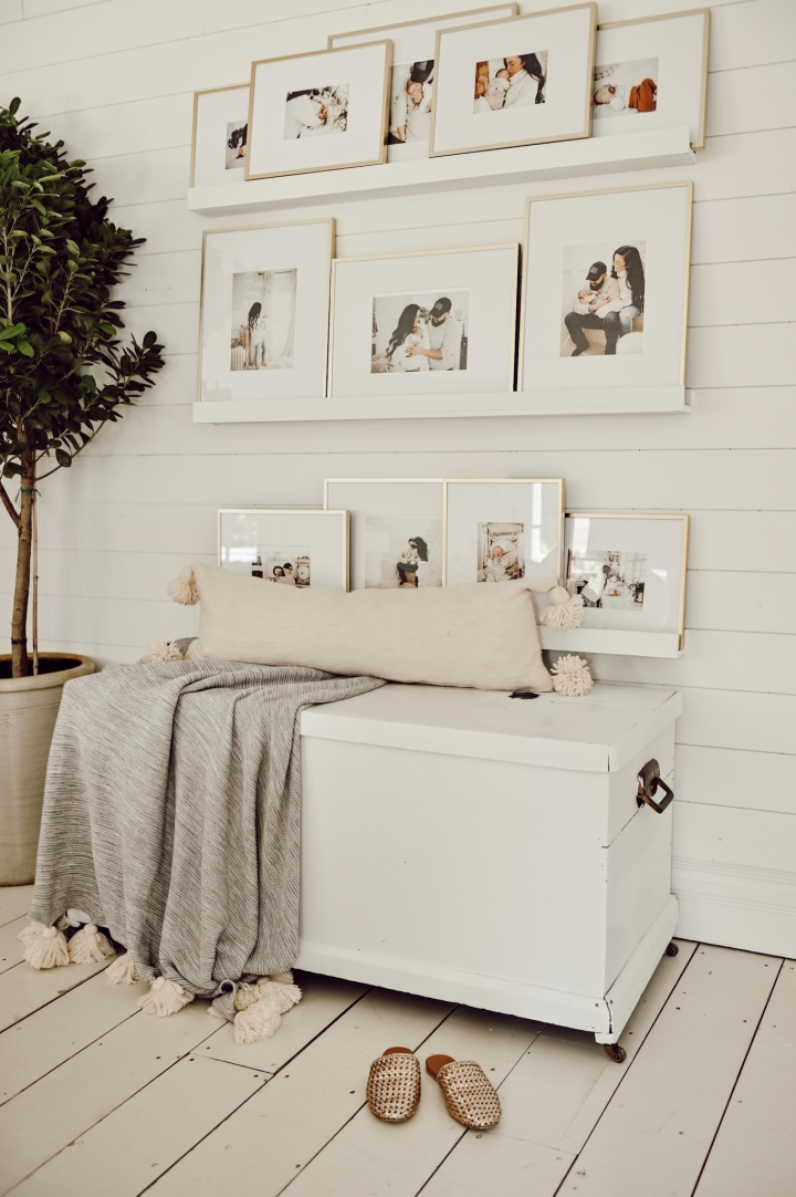 3 white picture ledges on a shiplap wall featuring family photos. 