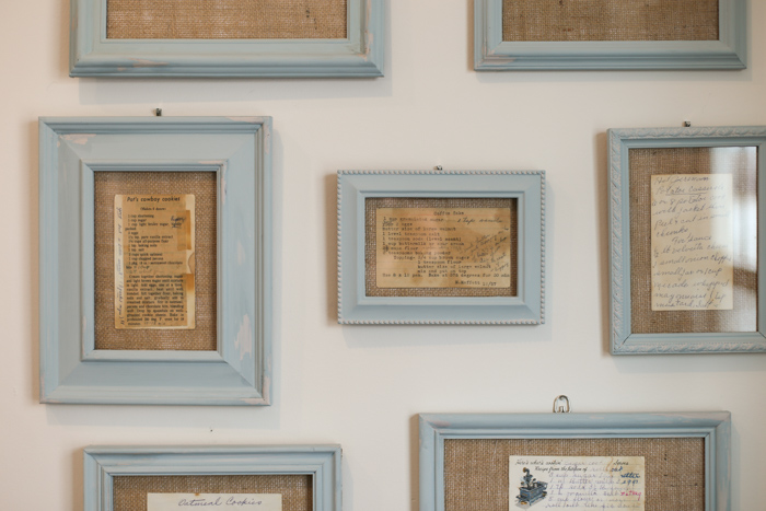 Family recipes in light blue painted frames, on a kitchen wall. 
