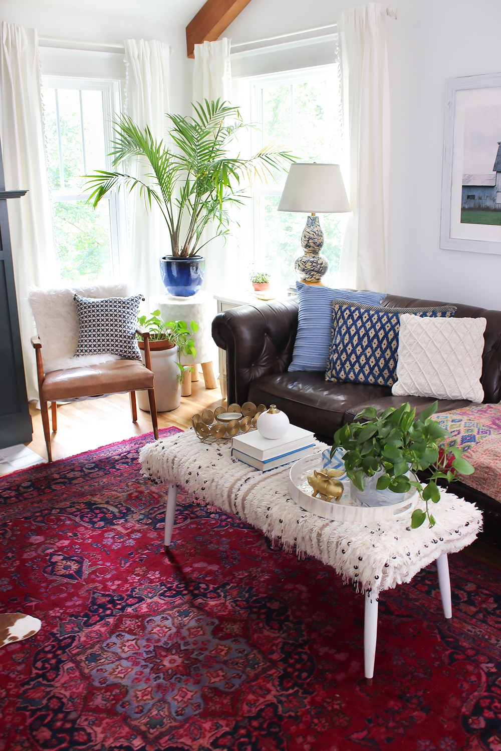 a small eclectic living room space with a leather sofa, small leather chair and a textured bench used as a coffee table