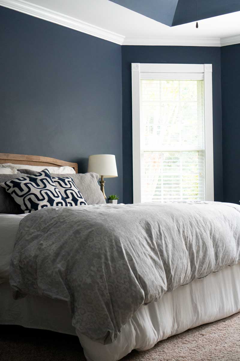 Bedroom with navy blue on the walls and ceiling, white painted trim and gray bedding