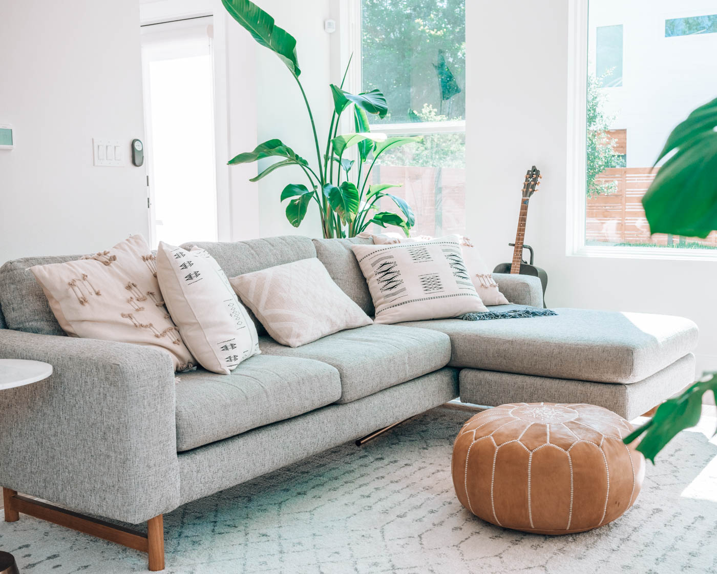 A small living room with a sectional sofa and a pouf for a coffee table