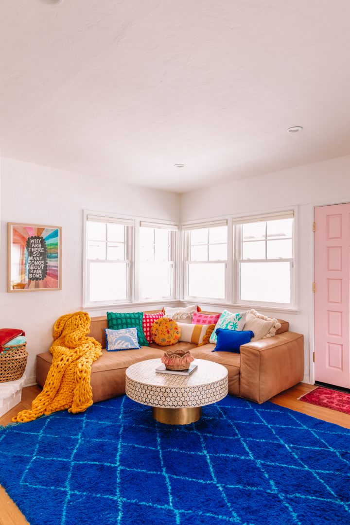 An L-shaped sectional sofa in the corner of a brightly colored living room. 